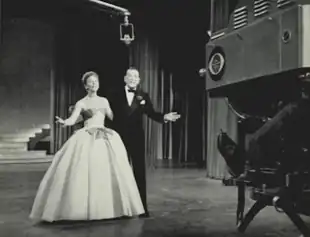 middle-aged white woman and white man in evening costume in a recording studio