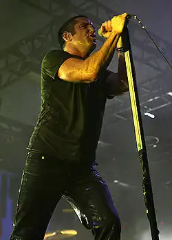 A man dressed in all black singing into a microphone.
