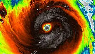 A close-up infrared satellite photograph of an extremely powerful tropical cyclone over the Mariana Islands. The entirety of Tinian is encapsulated in the eye of the storm, along with the southern tip of Saipan.