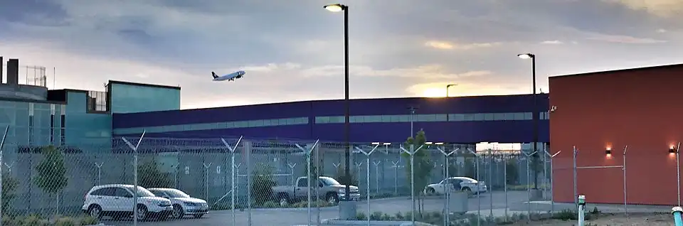 View of the Cross Border Xpress (CBX) bridge from parking lot on U.S. side, with Tijuana Airport on the left and the CBX U.S. terminal on the right