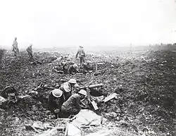 Two groups of soldiers are positioned in shallow holes on the battlefield, each manning a machine gun.