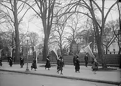 Young woman roller skating beside a group of women's suffragists at the White House, 1917