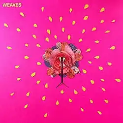 Over a pink background, a multi-colored flower surround by several yellow seeds, small yellow text displaying WEAVES on the top left