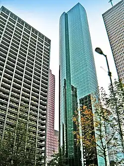 Tall, thin, glass tower with large, rounded outset on one side and strong vertical lines.