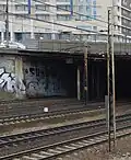 A black and chrome Fukow piece with pigeon character under a road bridge between Warsaw Ochota and Warsaw Main railway stations