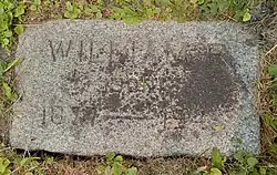 Flat grey granite marker engraved with the name William F, and the years 1877–1945
