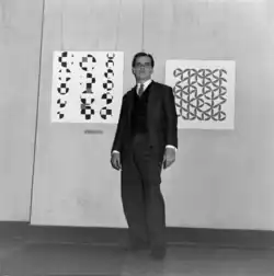 Willys de Castro in front of two of his paintings at the VI Salon of Modern Art in Rio de Janeiro, Brazil.